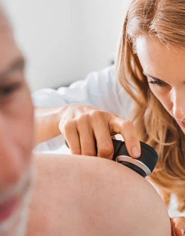 Provider examining a patient's shoulder with a dermatoscope