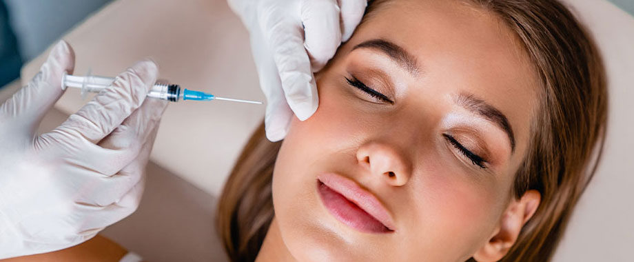 Woman with eyes closed receiving a cosmetic injection in her cheek