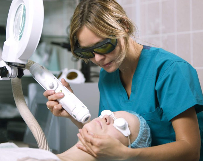 Provider in laser safety glasses treating a patient's face with a laser handpiece