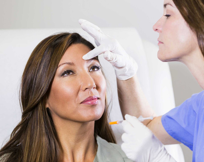 Gloved provider with a syringe treating a woman's face